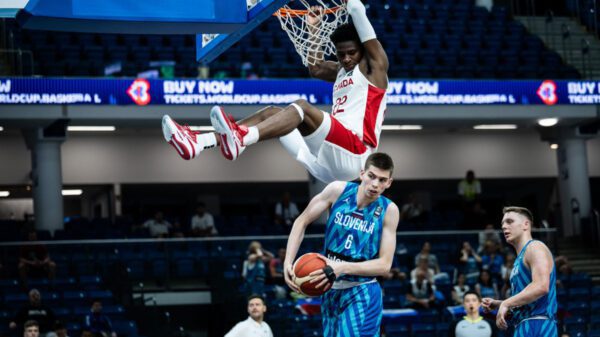 Canadian guard Elijah Fisher hangs on the rim after throwing down an emphatic dunk as Canada defeats Slovenia 90-69 to advance to the quarter-finals of the 2023 FIBA U19 World Cup.