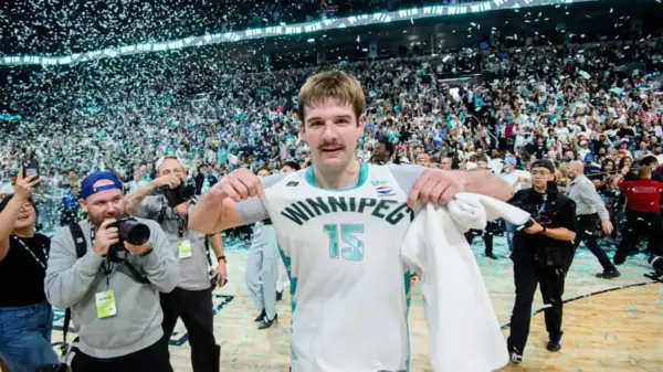 Simon Hildebrandt points to the Winnipeg Sea Bears logo on his jersey as photographers capture the moment and confetti falls from the rafters after his game-winning three-pointer gave Winnipeg its first CEBL championship.