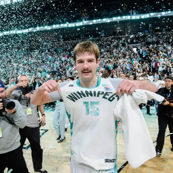 Simon Hildebrandt points to the Winnipeg Sea Bears logo on his jersey as photographers capture the moment and confetti falls from the rafters after his game-winning three-pointer gave Winnipeg its first CEBL championship.
