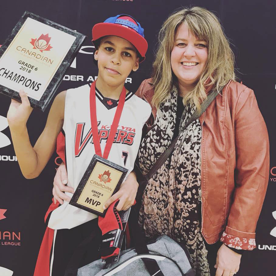 William riley standing beside his mother while holding up the 2018 canadian youth basketball league grade 6 mvp and champions plaques
