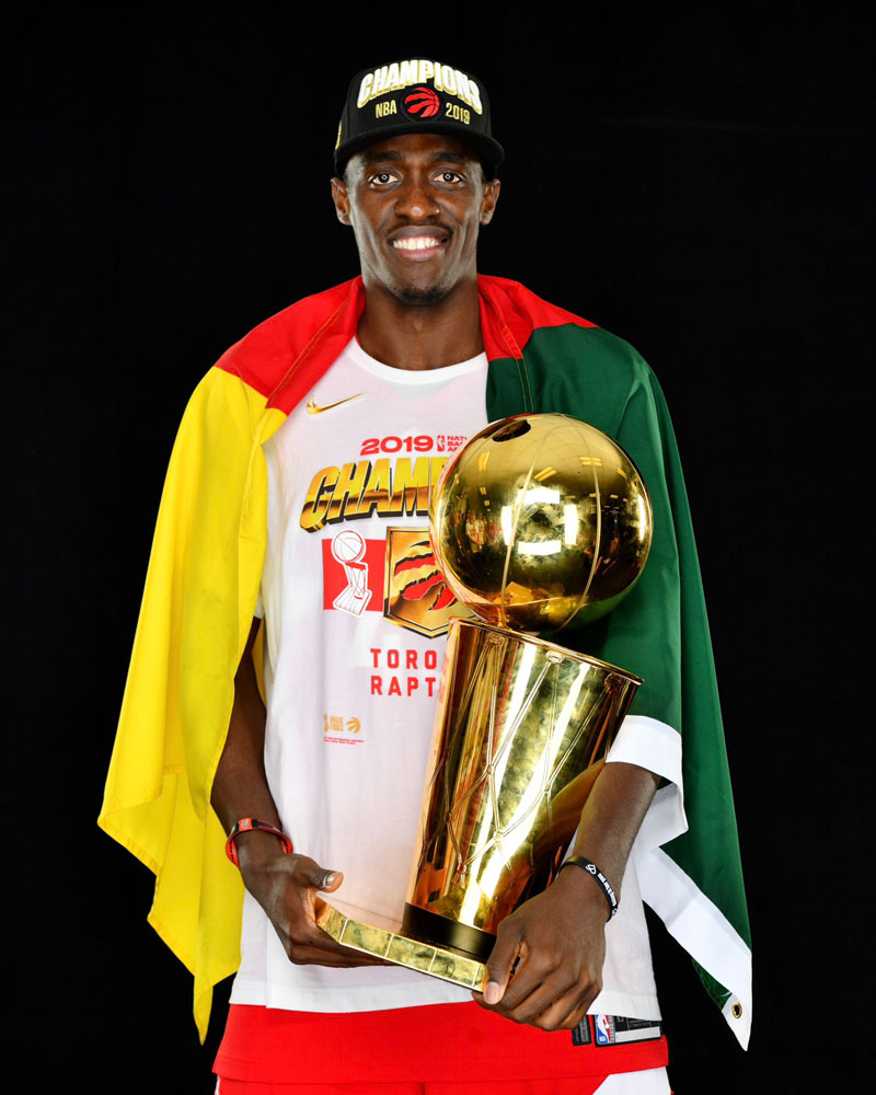 Wrapped around a cameroon flag pascal siakam poses with 2019 larry obrien championship trophy